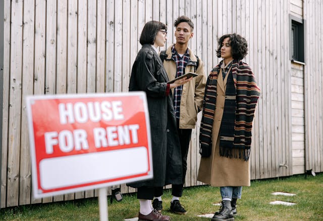 pexels-ivan-s-8962336 A landlady talking to a potential tenant couple behind a "For Rent" sign