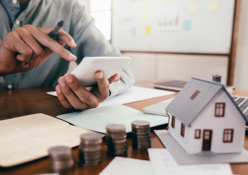 person-using-a-calculator-with-stacks-of-coins-in-front-of-them
